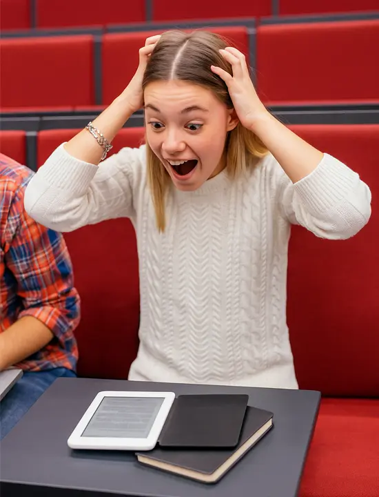 Studentessa in aula con espressione scioccata guarda un tablet sul banco, simbolo dell’uso crescente dell’IA tra gli studenti