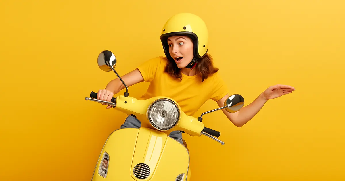 Studentessa sorridente in scooter giallo con casco, simbolo di ottimismo e sicurezza per gli esami 2025 con diritti DSA