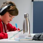ADHD a scuola - un ragazzo che mentre fa i compiti ascolta la musica e sta al pc