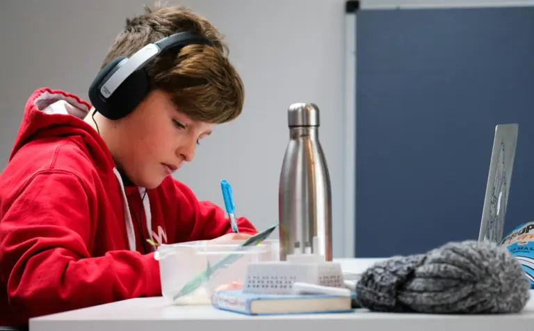 ADHD a scuola - un ragazzo che mentre fa i compiti ascolta la musica e sta al pc